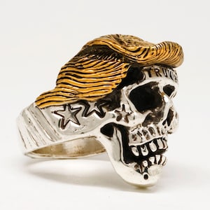 Anillo de calavera de Trump de acero inoxidable con cabello de oro de 18 k. Tallas disponibles: 9, 10, 12, 13, 15, 17, 18, 19 y 20.