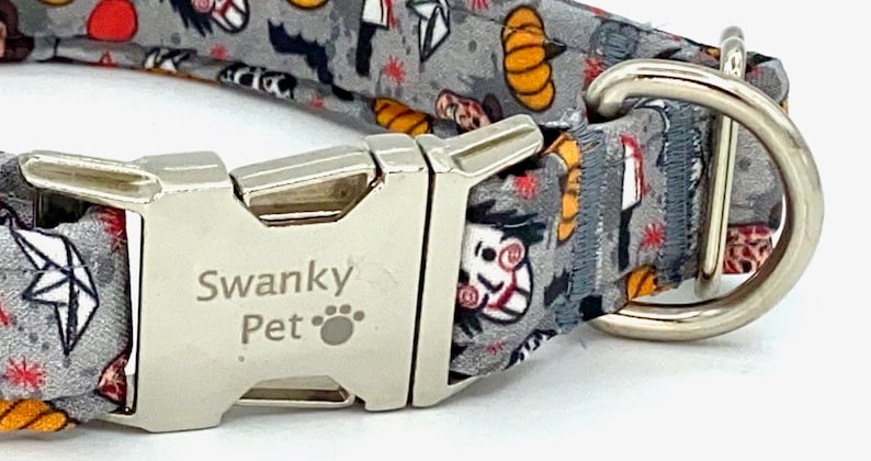 May include: A gray dog collar with a Halloween-themed pattern featuring pumpkins, bats, and a scary face. The collar has a silver metal buckle and a D-ring. The text "Swanky Pet" is printed on the buckle.