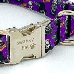 May include: Purple dog collar with a silver metal buckle and a D-ring. The collar features a repeating pattern of Frankenstein's monster and other horror-themed graphics. The buckle is engraved with "Swanky Pet".