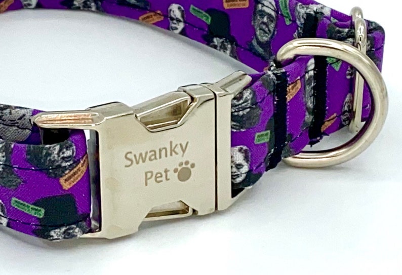 May include: Purple dog collar with a silver metal buckle and a D-ring. The collar features a repeating pattern of Frankenstein's monster and other horror-themed graphics. The buckle is engraved with "Swanky Pet".
