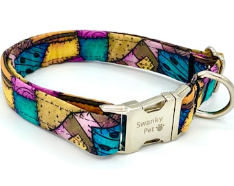 May include: A colorful dog collar with a patchwork design in shades of yellow, purple, teal, and brown. The collar has a silver metal buckle and a D-ring. The text "Swanky Pet" is visible on the buckle.