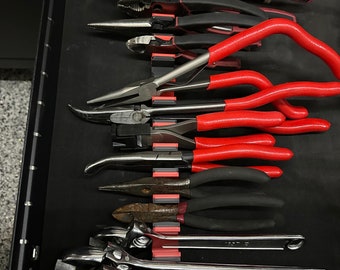 May include: A drawer organizer with a red and black magnetic strip holding a variety of pliers and wrenches. The tools include needle-nose pliers, wire cutters, and adjustable wrenches.