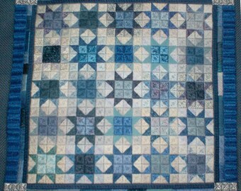 May include: A blue and white quilt with a star pattern. The quilt is framed with a blue border.