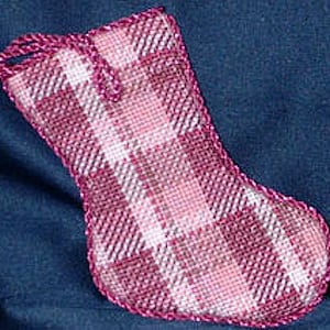 May include: A pink and white plaid stocking with a pink cord loop at the top. The stocking is made of a soft, textured fabric and has a scalloped edge.