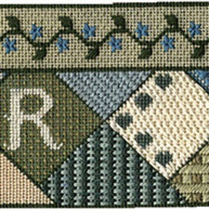 Puede incluir: Un lienzo de punto de aguja con un diseño de patchwork que presenta una variedad de patrones azules, verdes y blancos. El centro del lienzo presenta una gran letra "R" verde.