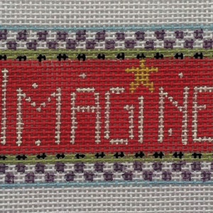 May include: A red cross-stitch sampler with a white border and a purple and green checkered border. The sampler says "Imagine" with a yellow star.