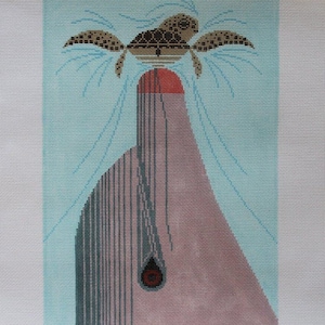 May include: A needlepoint canvas with a design of a stylized turtle with brown and black markings, perched on top of a pink and gray mountain with a red top. The turtle is surrounded by blue and white lines that resemble water.