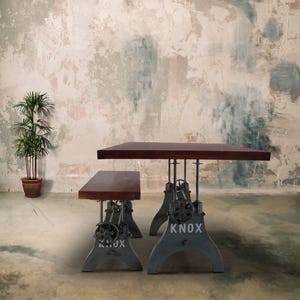 May include: A dark brown wooden table and bench set with a gray metal base. The table and bench have adjustable legs with a crank. The base of the table has the word "KNOX" printed on it.