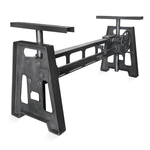 May include: A dark gray, industrial-style table base with a mechanical crank system. The base features a rectangular frame with a gear system and a hand crank wheel. The table base has two horizontal supports on top, and is made of metal.