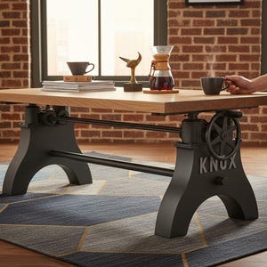 May include: A rectangular wooden coffee table with a light brown surface and black metal base. The base has a gear and wheel design with the word "KNUX" on the side. A coffee maker, cups, and decorative items are on the table.