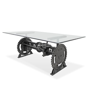 May include: A glass-top dining table with a unique industrial design. The base features a series of interconnected gears and metal rods, giving it a steampunk aesthetic.