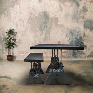 May include: A black rectangular table and bench set with industrial-style metal bases. The bases are gray with the word "KNOX" in white. A potted plant is in the background. The table is approximately 72 inches long.