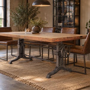 May include: A rectangular wooden dining table with a thick, natural-toned top supported by a heavy-duty, dark gray metal base featuring an adjustable hand crank mechanism, accompanied by four brown leather chairs with black metal frames.