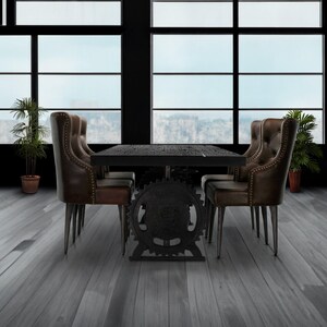May include: A dark wood dining table with a black metal base featuring a large gear design. The table is surrounded by four brown leather chairs with button tufting.