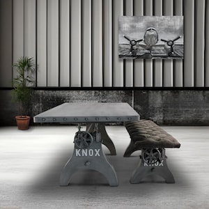 May include: Industrial-style dining table and bench set. The gray table has a rectangular top with metal accents and adjustable legs. The bench has a tufted cushion. The word "KNOX" is printed on the table and bench legs.