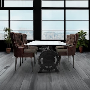 May include: A glass-top dining table with a metal base featuring a large gear design. The table is surrounded by four brown upholstered chairs with button tufting and studded trim.