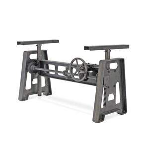 May include: A dark gray metal table base featuring an adjustable crank mechanism with a central handwheel, two vertical support columns with gear-driven height adjustment, and two horizontal top mounting plates for a tabletop surface.