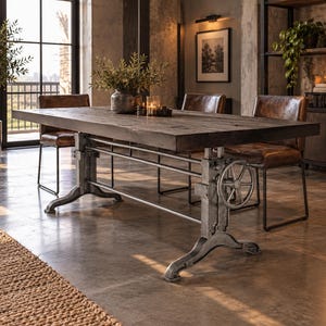 May include: A rectangular dining table with a dark wood top and a heavy-duty industrial metal base featuring a hand crank wheel for height adjustment. The table is accompanied by three brown leather chairs with thin black metal frames.