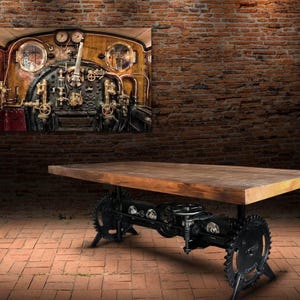 May include: A rustic wooden table with a black metal base featuring gears and a train engine design. The table top is made of reclaimed wood and has a natural finish. The base is made of heavy-duty metal and has a black powder coat finish.