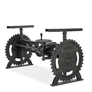 May include: A dark gray industrial-style table base featuring large gear wheels and a hand crank. The base has two rectangular supports for a tabletop. The design incorporates multiple gears and mechanical elements, creating a unique, vintage aesthetic.
