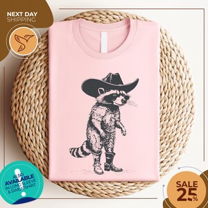 a pink shirt with a raccoon wearing a cowboy hat