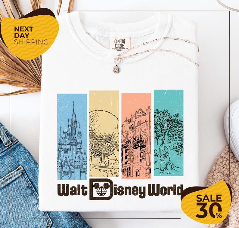 a white t-shirt with a graphic design depicting various landmarks and buildings from Walt Disney World, including the Eiffel Tower, the castle, and the roller coaster. The t-shirt is displayed on a white background, and there are yellow and black sale tags indicating a 30% discount.
