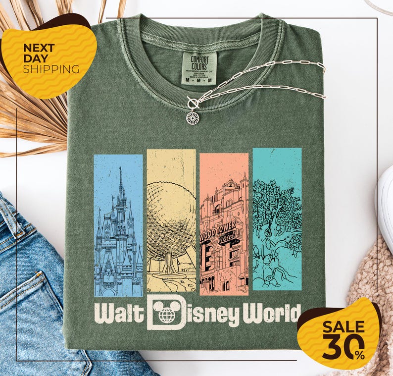 a green t-shirt with a graphic design of Disney World landmarks, including a castle, roller coaster, and other iconic structures. The t-shirt is displayed on a white background, and there are two yellow sale tags visible, one on the left and one on the right, indicating a 30% discount on the item.