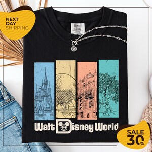a black t-shirt with a graphic design depicting various landmarks and attractions from Walt Disney World, including the Eiffel Tower, the Disney castle, and the Wood Tower. The t-shirt is displayed on a white background, and there are two yellow sale signs indicating a 30% discount on the item.