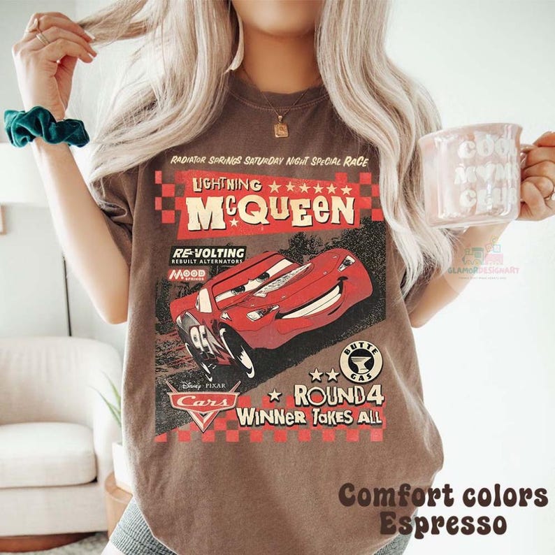 Może przedstawiać: Koszulka w kolorze espresso z grafiką Zygzaka McQueena z filmu Disney Pixar Auta. Projekt zawiera tekst "Lightning McQueen", "Round 4" i "Winner Takes All". Część kolekcji "Comfort Colors".