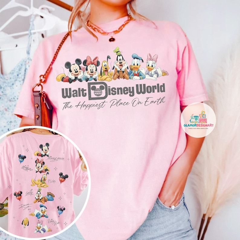 May include: A pale pink t-shirt with the words "Walt Disney World" and "The Happiest Place On Earth." The shirt features cartoon characters Mickey Mouse, Minnie Mouse, Pluto, Goofy, Donald Duck, and Daisy Duck. The back of the shirt has additional character graphics.