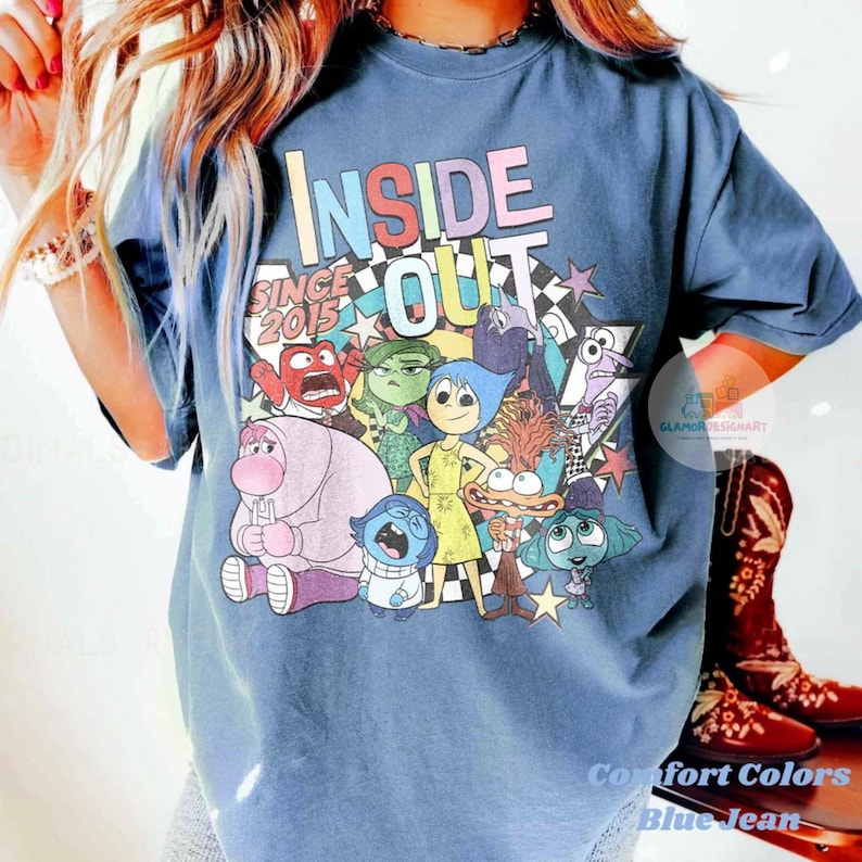 Pu&ograve; includere: T-shirt Comfort Colors blu jeans con una grafica colorata dei personaggi del film d'animazione "Inside Out". Il design include il testo "INSIDE OUT" e "SINCE 2015."