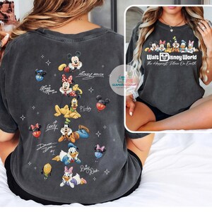 May include: Dark grey t-shirt featuring Disney characters Mickey Mouse, Minnie Mouse, Pluto, Goofy, Donald Duck, and Daisy Duck. The shirt includes the text "Walt Disney World The Happiest Place On Earth."
