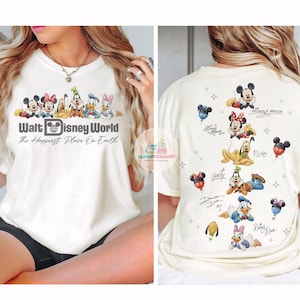 May include: Cream-coloured t-shirt featuring a Walt Disney World graphic with Mickey Mouse, Minnie Mouse, Donald Duck, and other characters. The back of the shirt displays additional Disney characters and signatures.