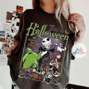 May include: Dark grey t-shirt with a Halloween graphic. The design features the text "This is Halloween" and "Everybody Make A Scene", alongside illustrations of Jack Skellington, Sally, and other characters from the movie.