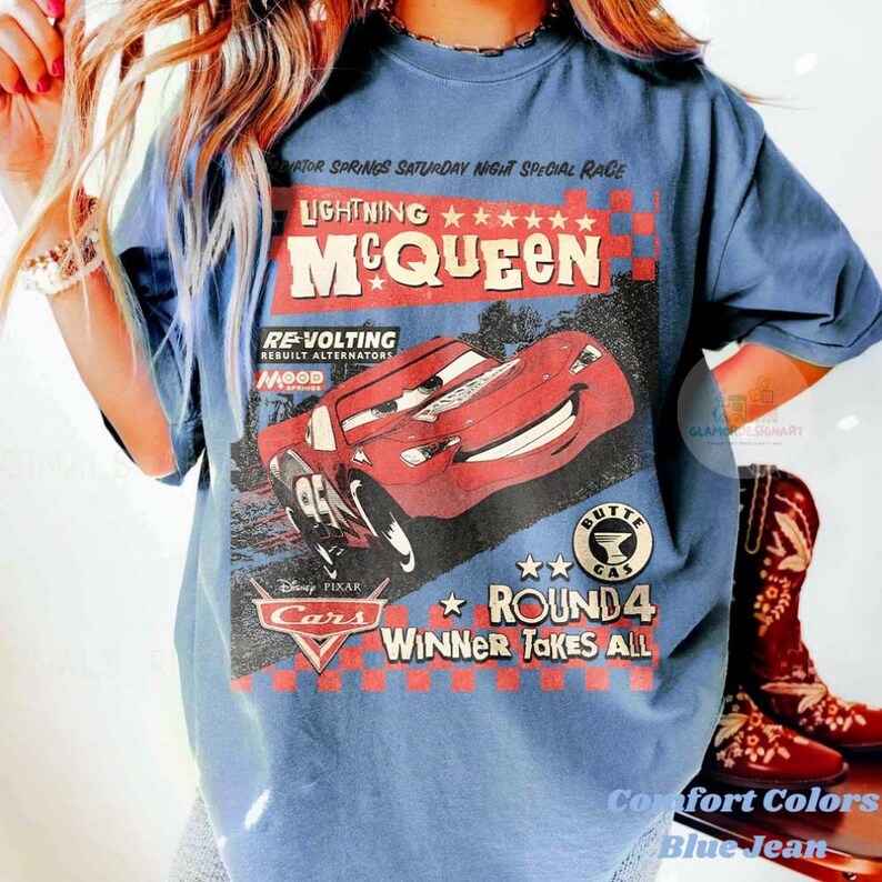 Może przedstawiać: Niebieska koszulka Comfort Colors z grafiką Zygzaka McQueena z filmu Disney Pixar Auta. Projekt zawiera tekst "Lightning McQueen", "Round 4" i "Winner Takes All".