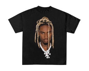 May include: A black short-sleeved t-shirt featuring a large, centered photographic print of a person with blonde dreadlocks and a dark complexion. The person is wearing a thick, silver-toned chain necklace with a prominent, detailed pendant.