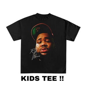 May include: Black t-shirt with a graphic of a man wearing a green and red baseball cap. The man's face is visible and the text "Rod Wave" is written in white below the image.