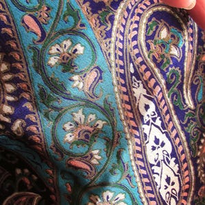 Puede incluir: Primer plano de una tela paisley azul y morada con un patrón floral rosa y blanco.