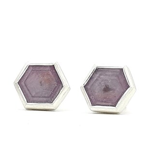 May include: A pair of silver stud earrings with hexagonal shaped purple gemstones.
