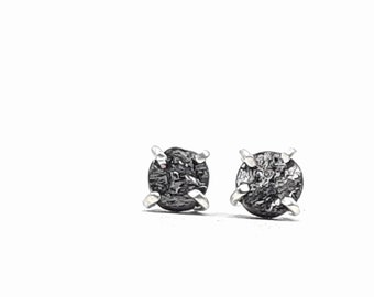 Peut inclure: Une paire de petites boucles d'oreilles rondes noires avec une surface texturée. Les boucles d'oreilles sont serties d'argent.