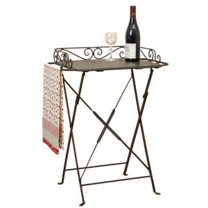 Könnte beinhalten: Ein Serviertisch aus Schmiedeeisen mit rechteckiger Platte und Klappbeinen. Eine Weinflasche, ein Weinglas und ein dekoratives Handtuch befinden sich auf dem Tisch. Der Tisch ist etwa 76 cm hoch.