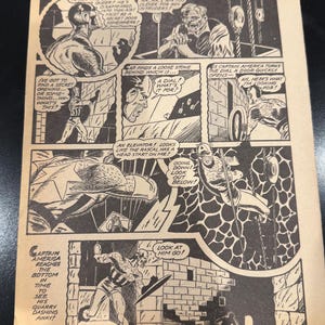 Può includere: Una pagina di fumetto vintage di Captain America in bianco e nero. I riquadri mostrano scene d'azione con fumetti. Il fumetto mostra Capitan America in varie pose, con testo come "Guardalo andare!" e "Un quadrante! A cosa serve?"