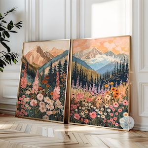 May include: Two framed illustrations of a mountain range with a field of wildflowers in the foreground. The mountains are painted in shades of blue and green, with a touch of white snow. The wildflowers are a mix of pink, purple, yellow, and white.