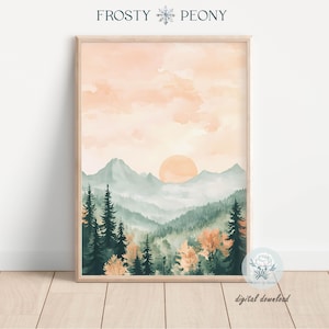 Peut inclure: Impression d'art de paysage à l'aquarelle représentant un coucher de soleil sur une chaîne de montagnes. L'œuvre comprend des arbres verts, des montagnes et un ciel orange et rose. L'impression est encadrée dans un cadre en bois clair. Le texte "Frosty Peony" et "digital download" sont visibles.