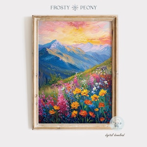 May include: A painting depicting a mountainous landscape with a field of colourful wildflowers in the foreground. The sky is a vibrant pink and orange, and the mountains are a deep blue. The painting is framed in a light wood frame.