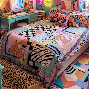 May include: A woven throw blanket featuring a vibrant 1990s-inspired geometric pattern with black and white checkerboards, pastel triangles, squiggles, and zebra stripes, finished with a fringed edge, draped over a bed with colorful pillows.