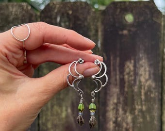 Vintage sterling silver earrings featuring a swirl design with dangling green glow beads and oxidized silver accents.