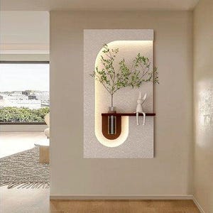 May include: A modern wall art piece featuring a rectangular textured panel with a U-shaped brown accent and a small shelf. A vase with greenery and a white rabbit figurine are on the shelf. The piece is illuminated with a warm light.