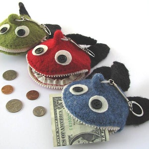 May include: Three felt zippered coin purses shaped like fish with large googly eyes. The fish are green, red, and blue. The purses have black felt fins and a silver key chain.