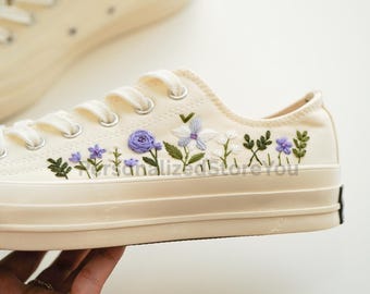 Pode incluir: Tênis de lona creme com desenhos florais bordados em roxo, branco e verde. Os sapatos de cano baixo apresentam cadarços brancos e sola de borracha. O texto "PersonalizedStoreYou" é visível na lateral.